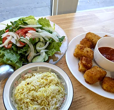 Garden salad, fried tofu with a dipping sauce and a bowl of rice on the table