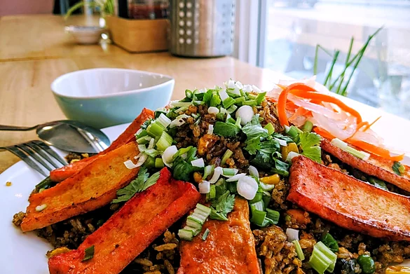 Fried rice topped with seared tofu slices, scallions and pickled carrot