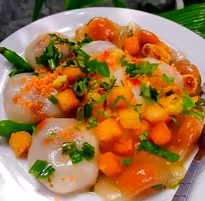 Plate of clear tapioca dumplings topped with fried tofu, scallions and chili