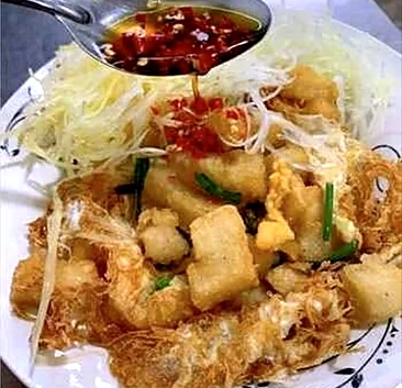 Crispy fried tofu on a nest of fried noodles with shredded vegetables and chili sauce