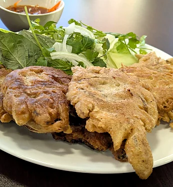 Golden vegetable fritters with lettuce, herbs and a dipping sauce