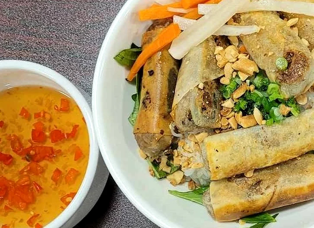 Spring Rolls Rice Vermicelli: Vermicelli bowl topped with crispy spring rolls, peanuts, scallions and pickled carrot and daikon, with dipping sauce
